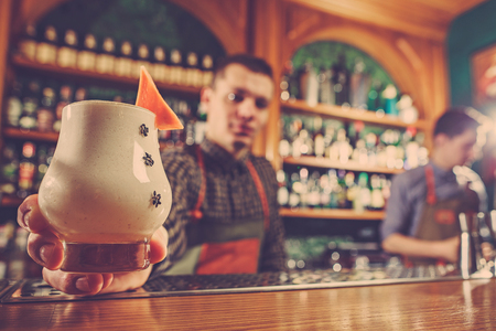 Barman offering an alcoholic cocktail at the bar counter on the bar backgroundの写真素材