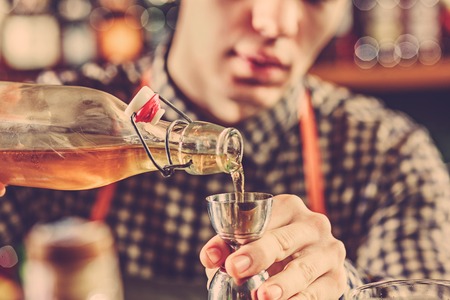 Barman making an alcoholic cocktail at the bar counter on the bar background