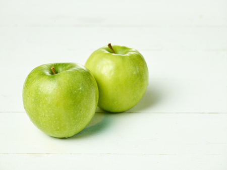 Shot of two fresh green apples with green leaf on a table.の写真素材