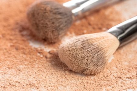 Close-up of crushed mineral shimmer powder golden color with makeup brush