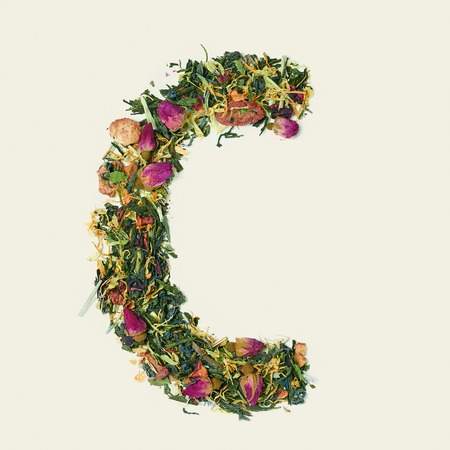 Tea leaf with flowers and fruits, letter C on white background, top viewの写真素材