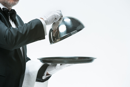 Close up waiter hand with tray and metal cloche lid coverの写真素材