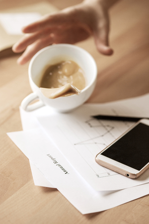 Coffee in white cup spilling on the table in the morning working day at office tableの写真素材