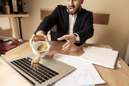 Coffee in white cup spilling on the table in the morning working day at office tableの写真素材