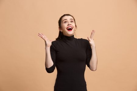 Beautiful woman looking suprised isolated on pastel brownish beigeの写真素材
