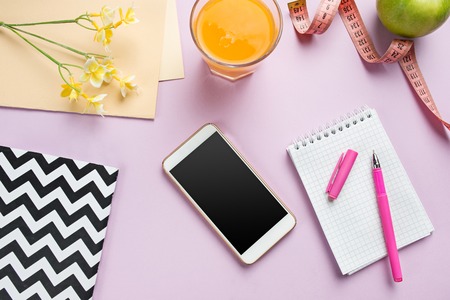 Top view of green apple, measuring tape, mobile phone, pen and open notebook. Fitness Concept.の写真素材