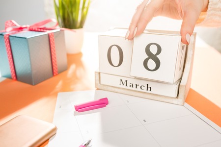 The side view of orange desk with cup of phone, gift, flowers and notebookの写真素材
