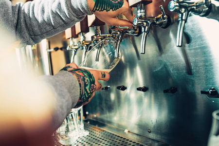 Hand of bartender pouring a large lager beer in tap.の写真素材