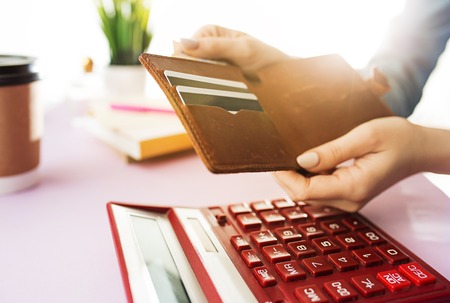 woman is holding purse, credit card in hands and calculating the costsの写真素材