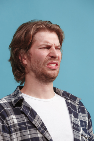 Let me think. Doubtful pensive man with thoughtful expression making choice against blue backgroundの写真素材