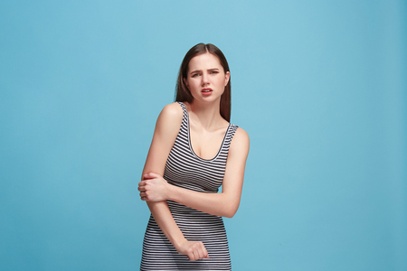The elbow ache. The sad woman with elbow ache or pain on a blue studio background.の写真素材