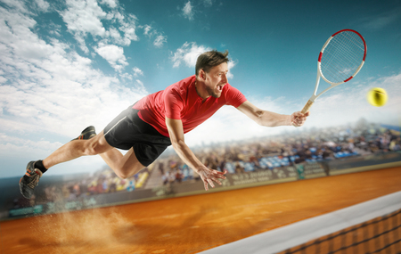 The one jumping player, caucasian fit man, playing tennis on the earthen court with spectatorsの写真素材