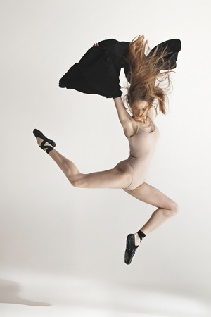 Young beautiful dancer in beige swimsuit dancing on gray backgroundの写真素材