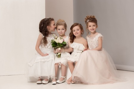 Little pretty girls with flowers dressed in wedding dressesの写真素材