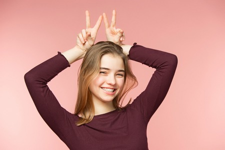 Woman smiling with perfect smile and white teeth on the pink studio background and looking at cameraの写真素材