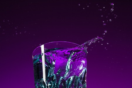 The water splashing in glass on lilac backgroundの写真素材
