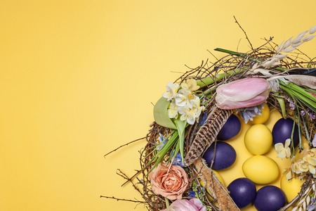 Easter card. Painted Easter eggs in nest on yellow backgroundの写真素材