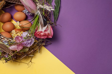 Easter card. Painted Easter eggs in nest on yellow background