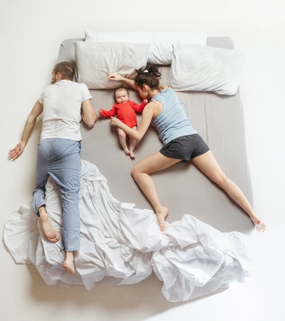 Top view of happy family with one newborn child in bedroom.の写真素材
