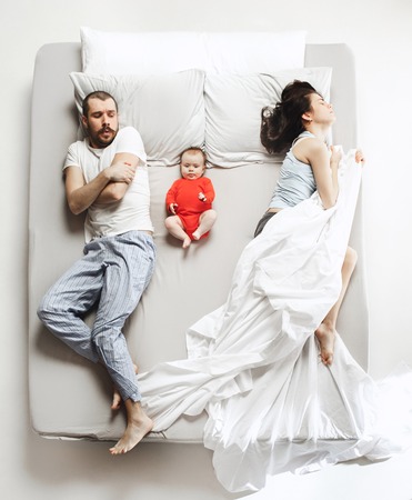 Top view of happy family with one newborn child in bedroom.の写真素材
