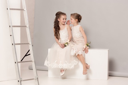Little pretty girls with flowers dressed in wedding dressesの写真素材