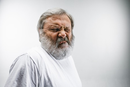 Senior man with disgusted expression repulsing something on white