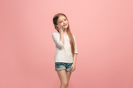 The happy teen girl standing and smiling against pink background.の写真素材
