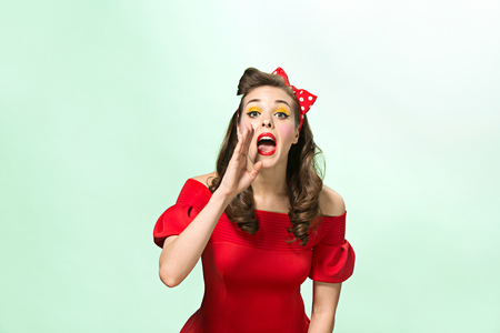 Beautiful young woman with pinup make-up and hairstyle. Studio shot on white backgroundの写真素材