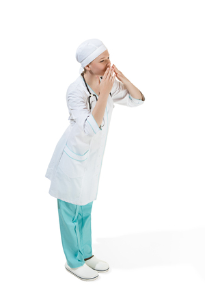 Beautiful young woman is sending an air kiss in white coat posing at studio. Full length studio shot isolated on white.の写真素材