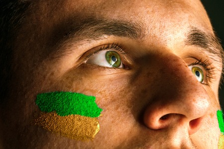 Portrait of a man with the flag of the Brazil painted on him face.の写真素材