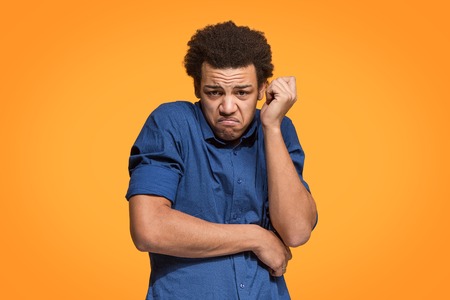 Let me think. Doubtful pensive man with thoughtful expression making choice against orange backgroundの写真素材