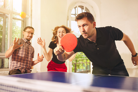 Group of happy young friends playing ping pong table tennisの写真素材