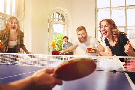 Group of happy young friends playing ping pong table tennisの写真素材