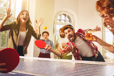 Group of happy young friends playing ping pong table tennisの写真素材