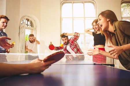 Group of happy young friends playing ping pong table tennisの写真素材