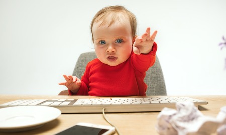 Happy child baby girl toddler sitting with keyboard of computer isolated on a white background
