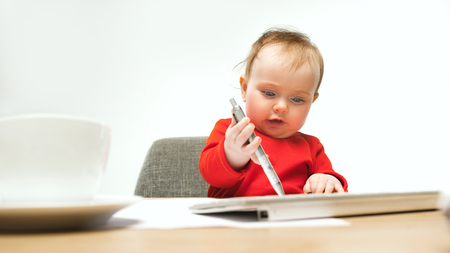 Happy child baby girl toddler sitting with keyboard of computer isolated on a white backgroundの写真素材