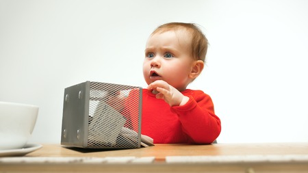 Happy child baby girl toddler sitting with keyboard of computer isolated on a white background