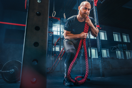 Men with battle rope battle ropes exercise in the fitness gym. CrossFit.の写真素材