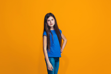The happy teen girl standing and smiling against orange background.の写真素材