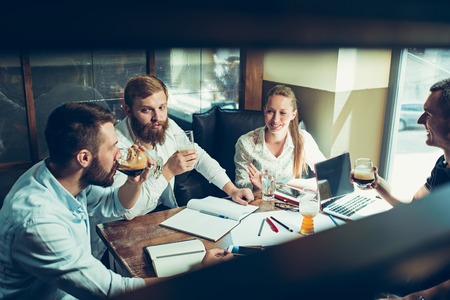 Young cheerful people smile and gesture while relaxing in pub.の写真素材