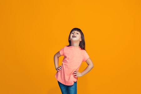 The happy teen girl standing and smiling against orange background.の写真素材
