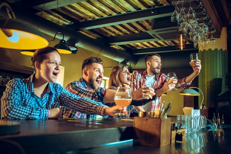 Sport, people, leisure, friendship and entertainment concept - happy football fans or male friends...