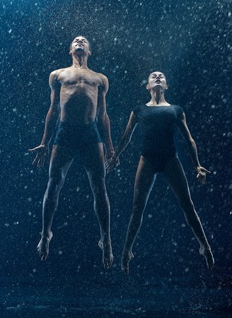Young couple of ballet dancers dancing unde rwater dropsの写真素材