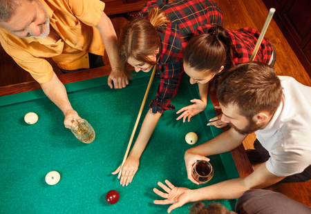 Young men and women playing billiards at office after work.の写真素材