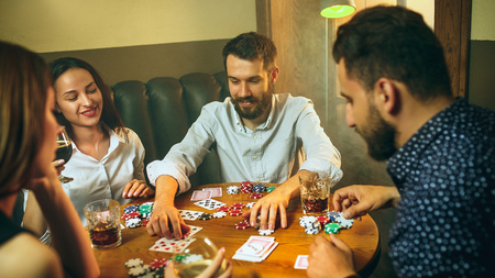 Side view photo of friends sitting at wooden table. Friends having fun while playing board game.の写真素材