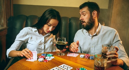 Side view photo of friends sitting at wooden table. Friends having fun while playing board game.の写真素材