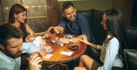 Side view photo of friends sitting at wooden table. Friends having fun while playing board game.の写真素材
