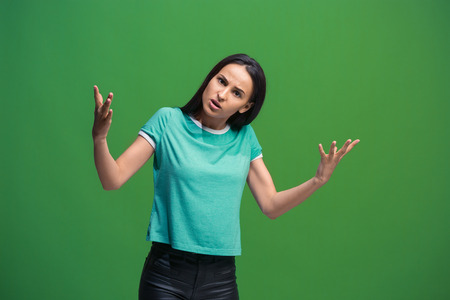 Beautiful female half-length portrait isolated on green studio backgroud. The young emotional...