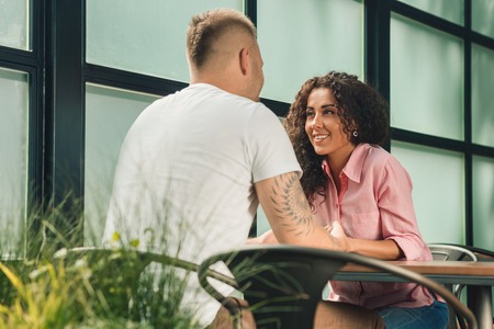 Close up on a man and a woman holding hands at a wooden tableの写真素材